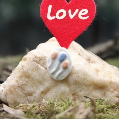 Peça decorativa com coração vermelho de feltro e pedra clara sobre musgo