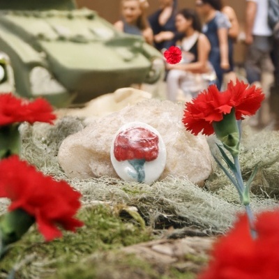 Miniatura de tanque verde com flores vermelhas e pedra com cravo pintado
