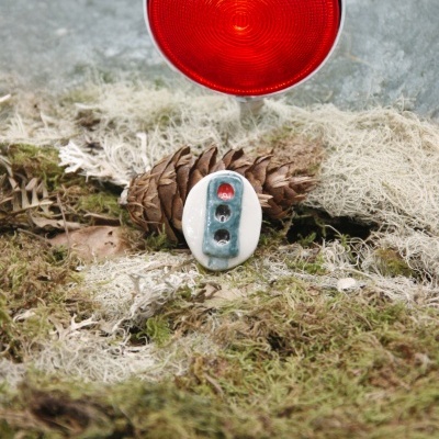 Cone de pinheiro, musgo e objeto cerâmico com luz vermelha ao fundo