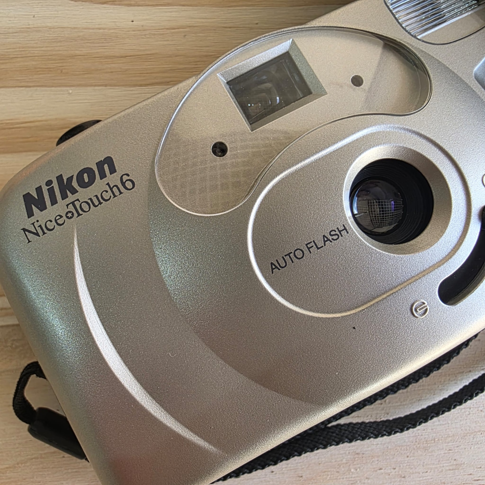 Nikon Nice Touch 6 Máquina fotográfica compacta Nikon prateada em cima de madeira clara