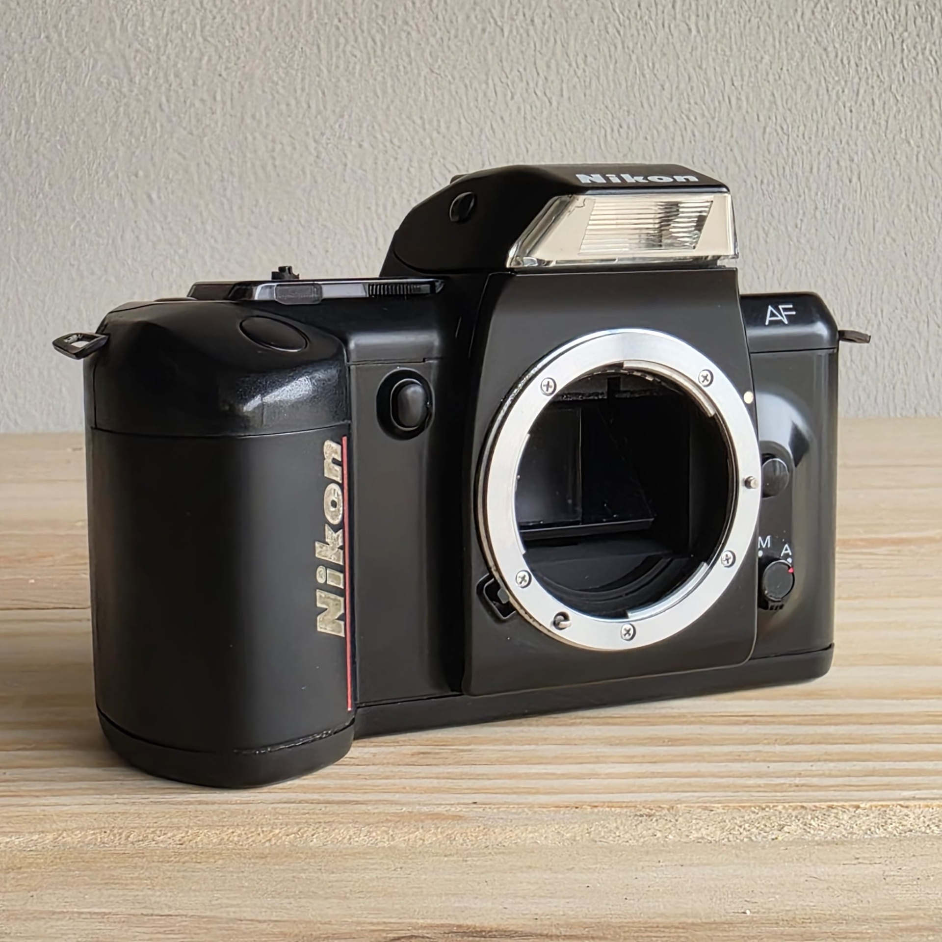 Nikon F4004 Câmara fotográfica analógica preta Nikon sem objetiva sobre mesa de madeira
