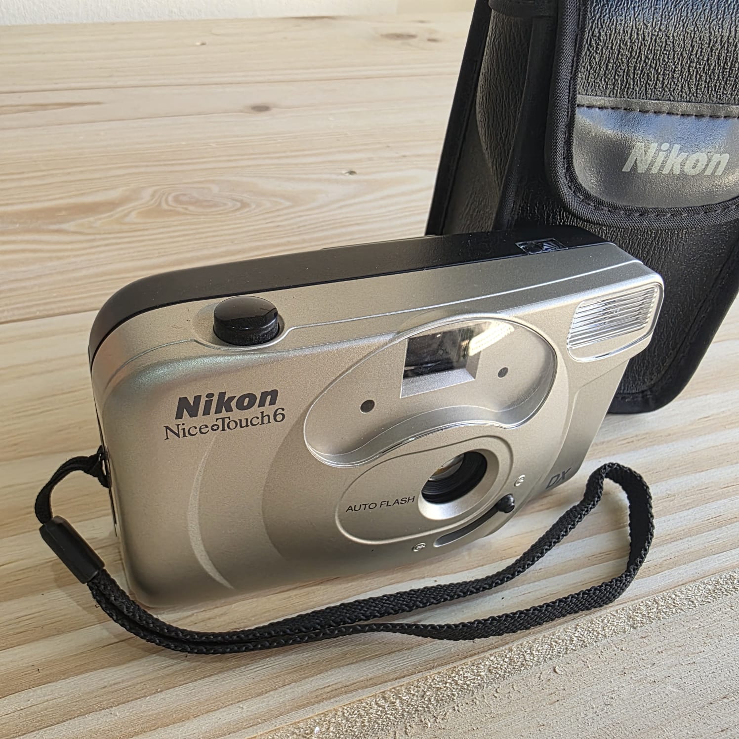Nikon Nice Touch 6 Máquina fotográfica compacta Nikon Nice Touch 6 prata e preto com bolsa preta numa mesa de madeira