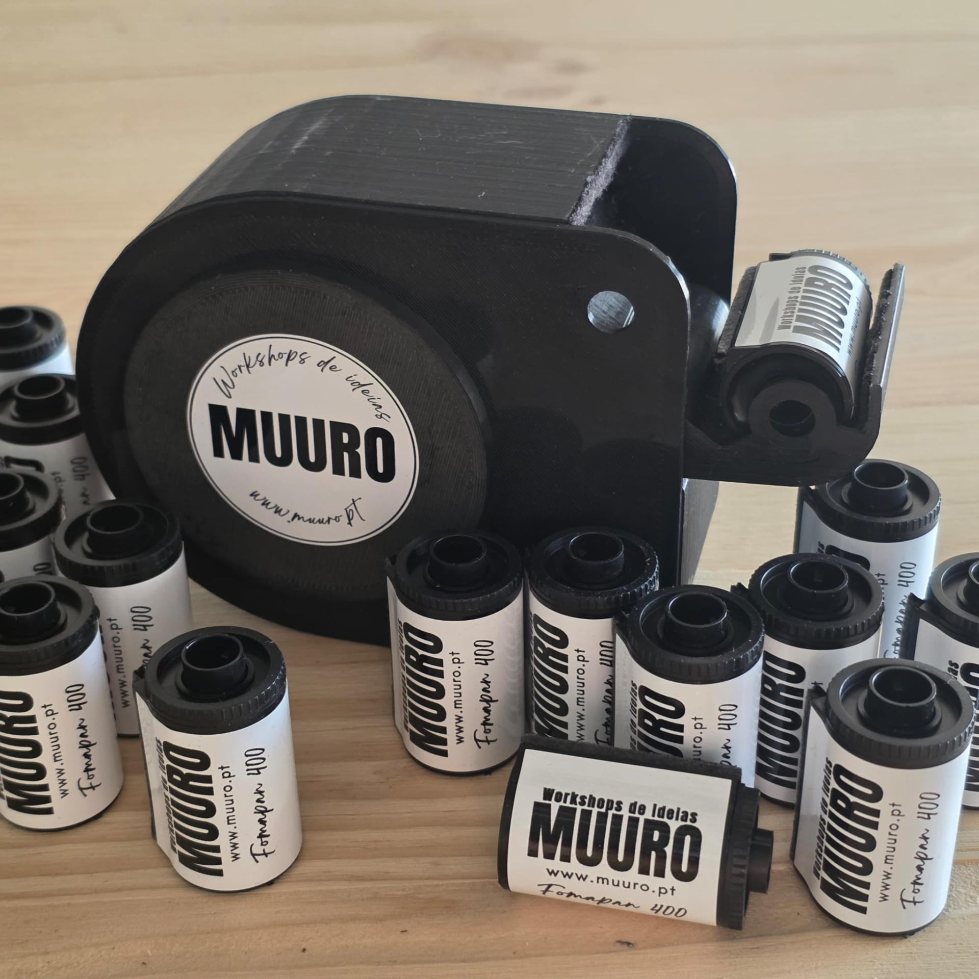 Rolos de filme fotográfico analógico MUURO e revelador preto numa mesa de madeira clara