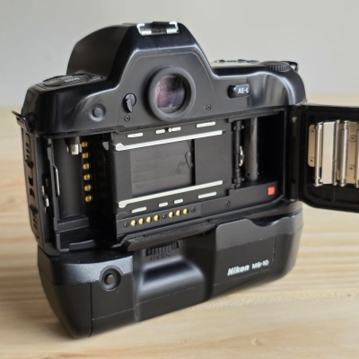 Câmara fotográfica clássica preta com porta traseira aberta mostrando interior e marca Nikon MB-10