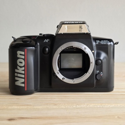 Câmara fotográfica Nikon F-401X preta sem lente sobre mesa de madeira