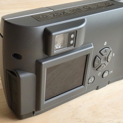 Câmara fotográfica digital preta vista de trás sobre uma superfície de madeira