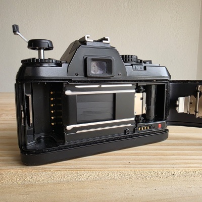 Máquina fotográfica analógica preta com compartimento de filme aberto