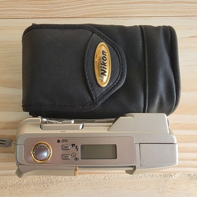 Máquina fotográfica compacta prateada com bolsa preta Nikon.