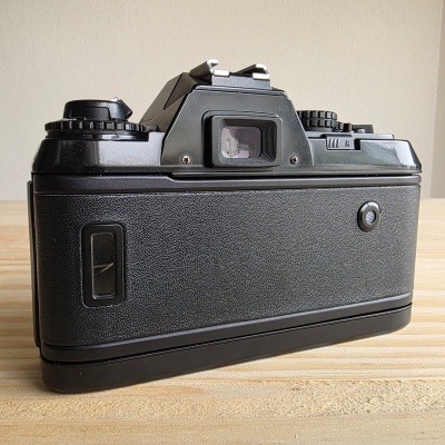 Câmara fotográfica analógica preta vista de trás sobre uma superfície de madeira clara