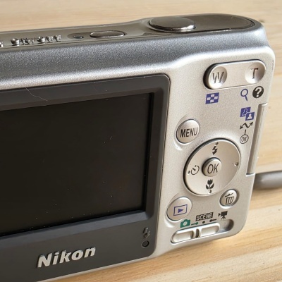 Câmara digital Nikon prateada com ecrã e botões visíveis