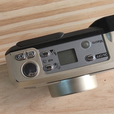 Câmara fotográfica digital preta e cinza com botões metálicos e ecrã