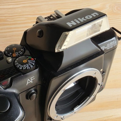 Máquina fotográfica analógica Nikon F-401X preta sem lente sobre madeira