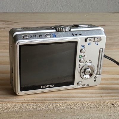 Câmara digital Pentax prateada com ecrã LCD e botões de controlo