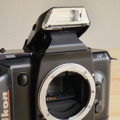 Máquina fotográfica SLR preta Nikon sem lente com flash embutido