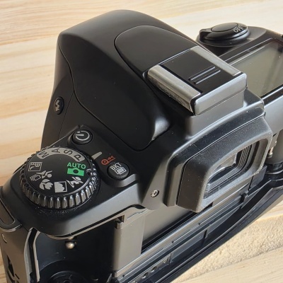Máquina fotográfica analógica preta com disco de modos e visor ótico