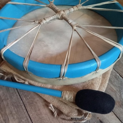 Tambor azul com pele esticada e baqueta azul e preta sobre tecido e madeira