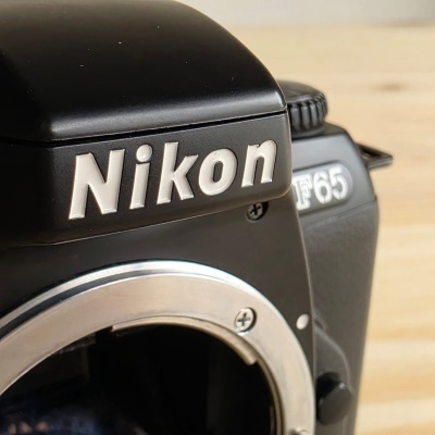 Máquina fotográfica reflex Nikon F65 preta com marcas visíveis