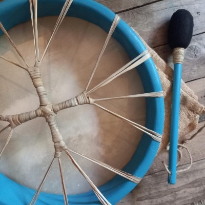 Tambor de mão azul com baqueta preta em superfície de madeira
