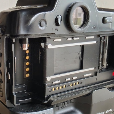 Câmara fotográfica Nikon preta com compartimento traseiro aberto