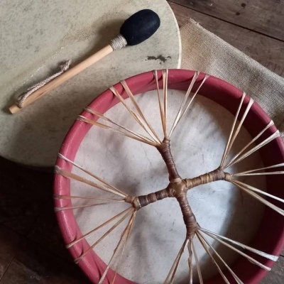 Dois tambores tradicionais com baqueta sobre mesa de madeira.