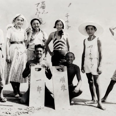 Grupo de jovens e crianças japonesas com roupas de verão e placas com escrita japonesa.