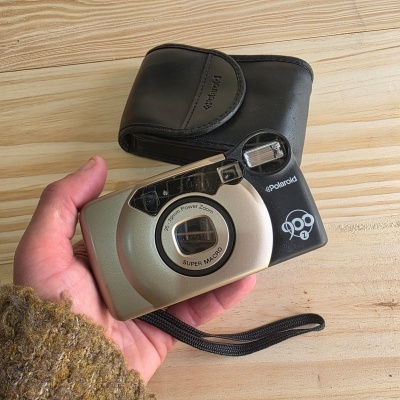 Câmara Polaroid 900 Z com estojo preto sobre madeira clara