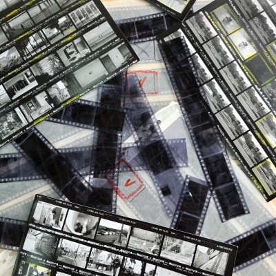 Folhas de contacto e negativos de filme fotográfico preto e branco ILFORD HP5 PLUS sobre uma superfície clara