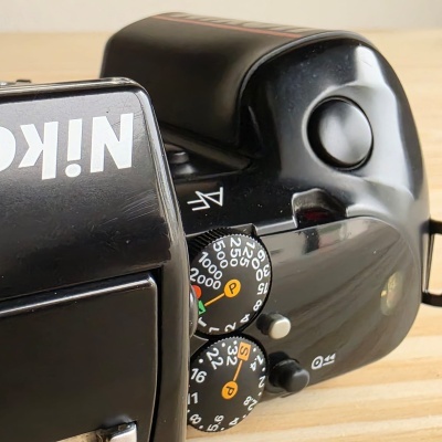 Câmara fotográfica analógica preta Nikon com botões de controlo