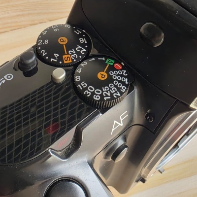 Mostradores e botões de uma câmara fotográfica vintage preta em superfície de madeira.