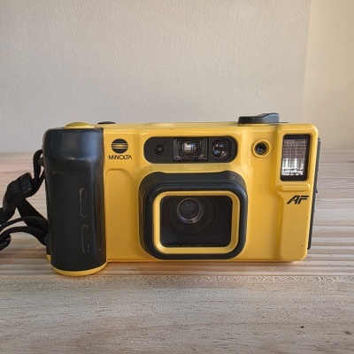 Câmara fotográfica Minolta amarela com empunhadura preta e flash integrado