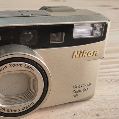 Máquina fotográfica Nikon branca com lente zoom 38-90 mm macro e flash