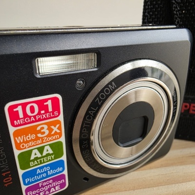 Máquina fotográfica digital preta com etiquetas coloridas e lente prateada