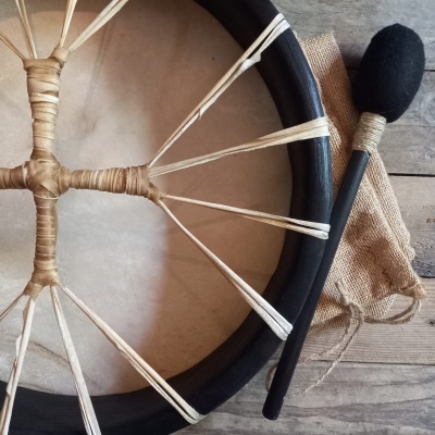 Pandeiro tradicional com marreta e tecido rústico num fundo de madeira