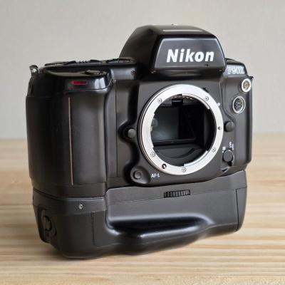 Câmara fotográfica analógica Nikon F90X preta sem objetiva sobre madeira clara