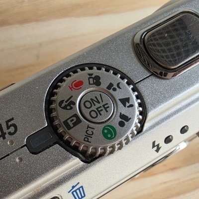 Roda de modo em câmera fotográfica prateada com botões e ícones