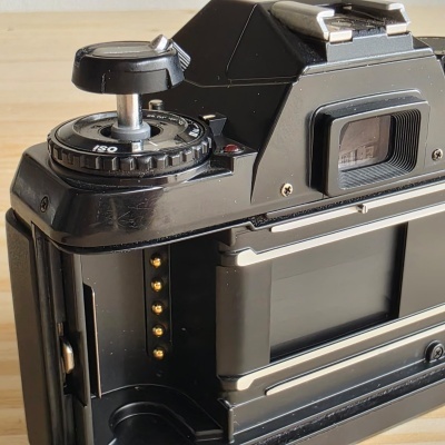 Parte traseira de câmara fotográfica analógica preta com ajustes ISO e visor