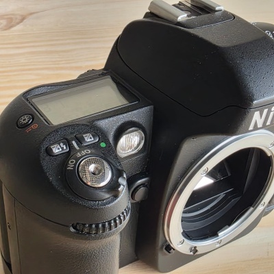 Máquina fotográfica DSLR preta da marca Nikon em cima de mesa de madeira