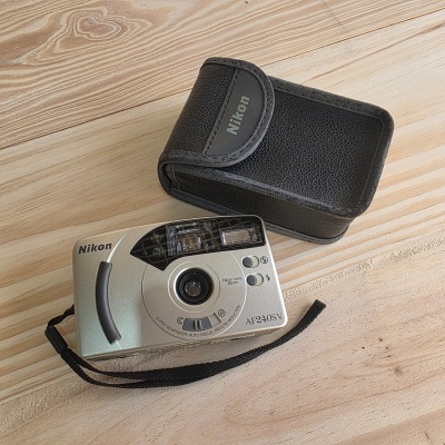 Câmara fotográfica compacta Nikon AF240SV prateada com estojo preto em madeira clara