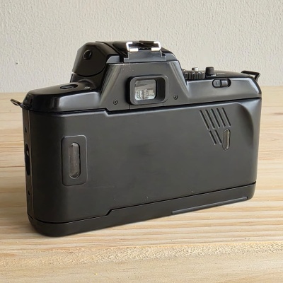 Câmara fotográfica analógica preta vista de trás sobre madeira