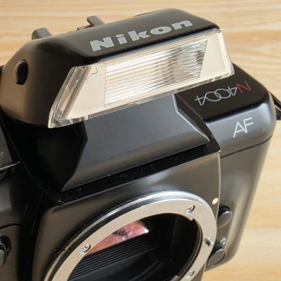 Câmara Nikon preta com flash incorporado e texto visível