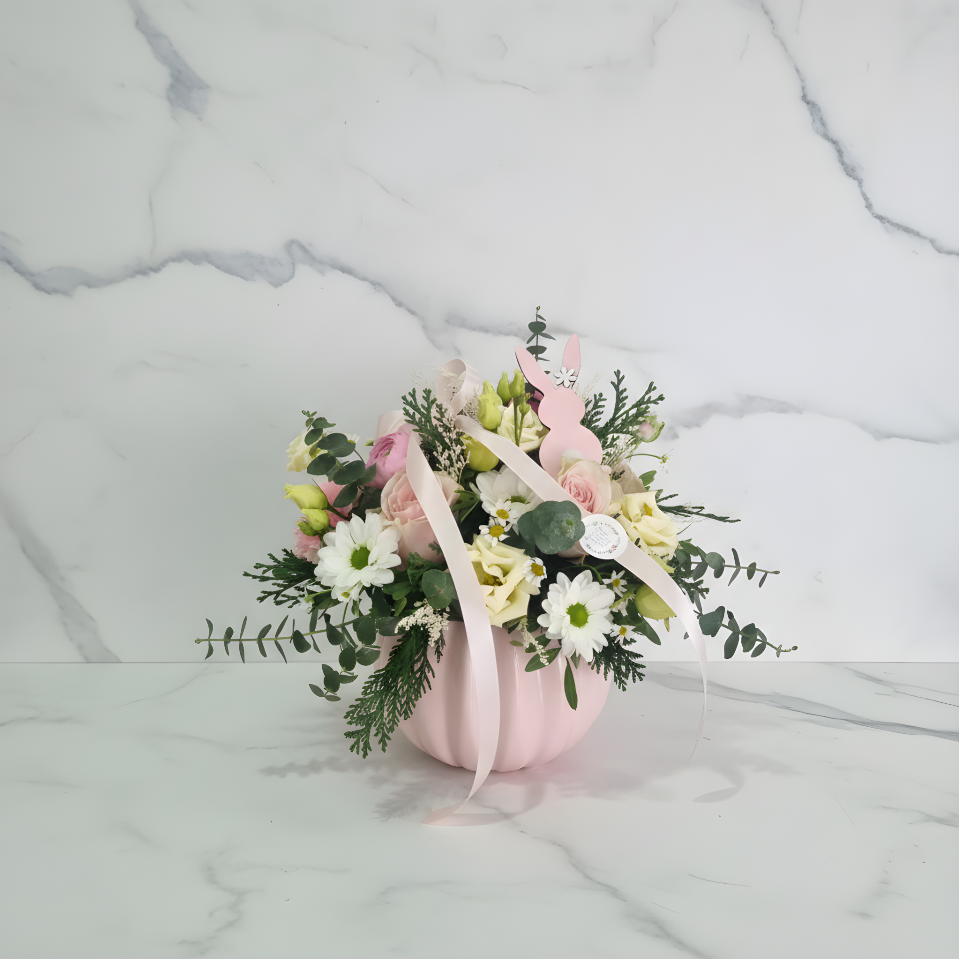 Arranjo floral em vaso rosa com flores brancas e rosas e decoração de coelho