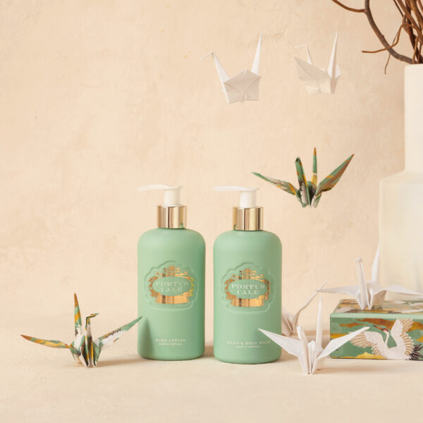 Frascos verdes com bombas douradas e figuras de origami de gansos em fundo bege.