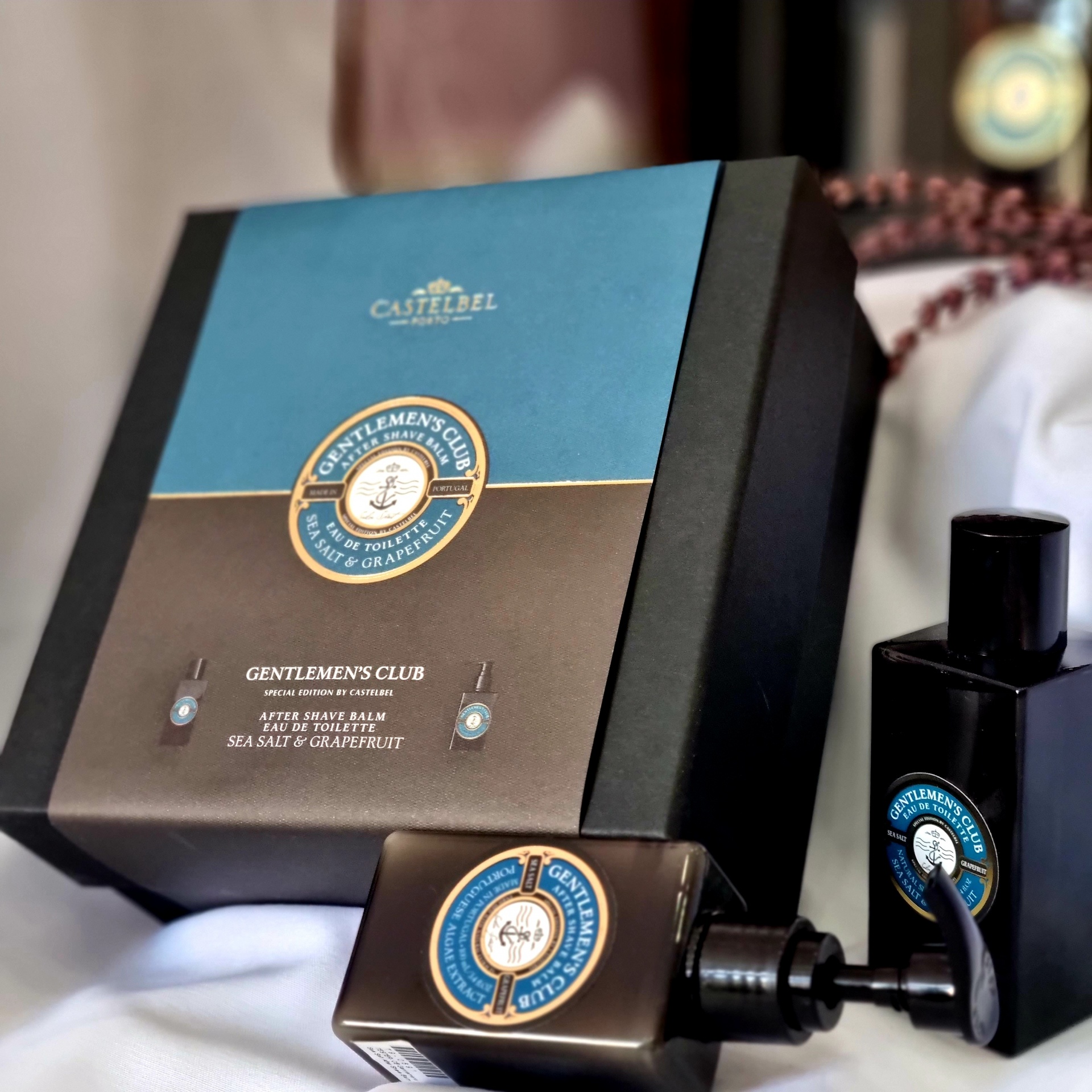 Caixa de embalagem preta e azul com frascos pretos em tecido branco