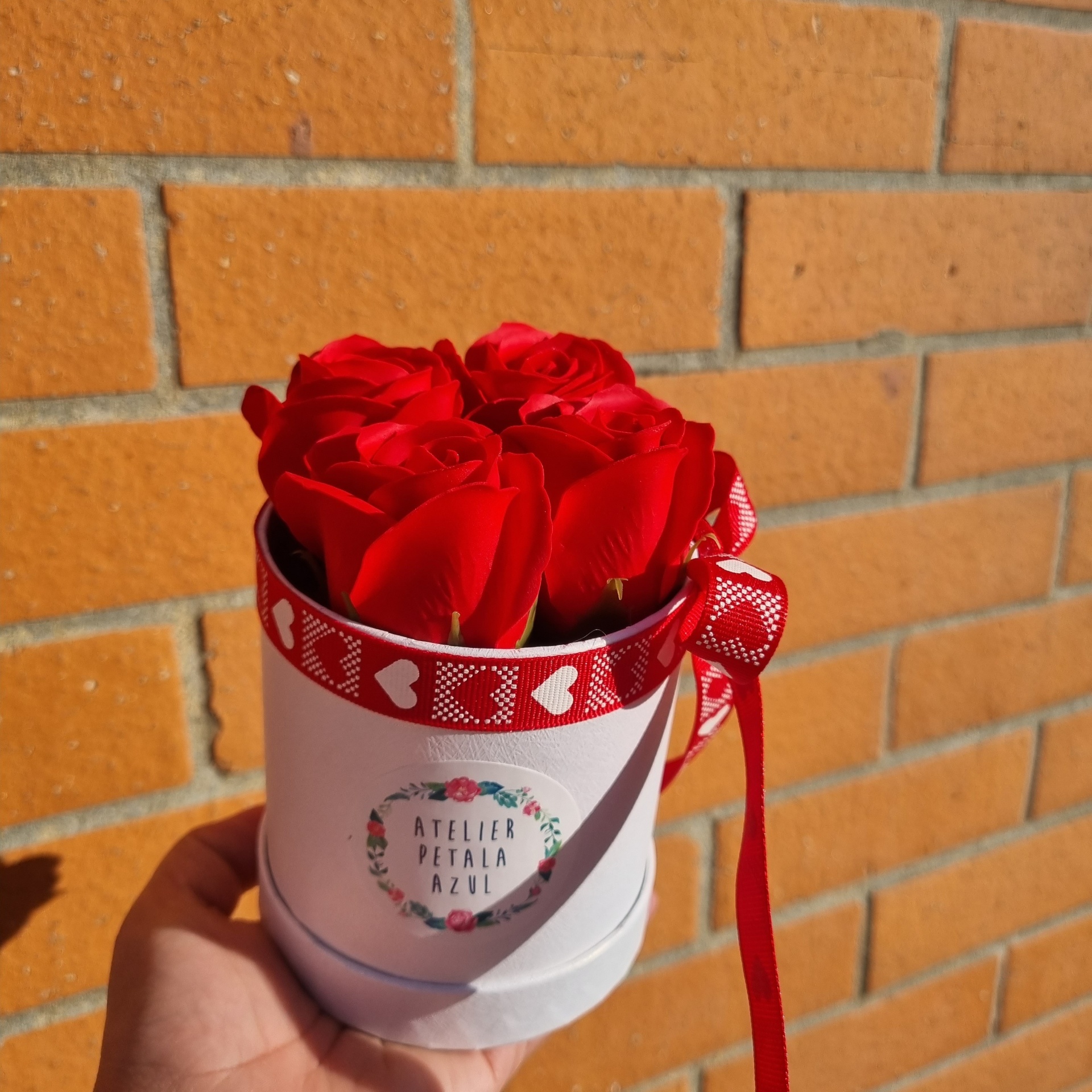 Vaso branco com rosas vermelhas e fita vermelha com corações