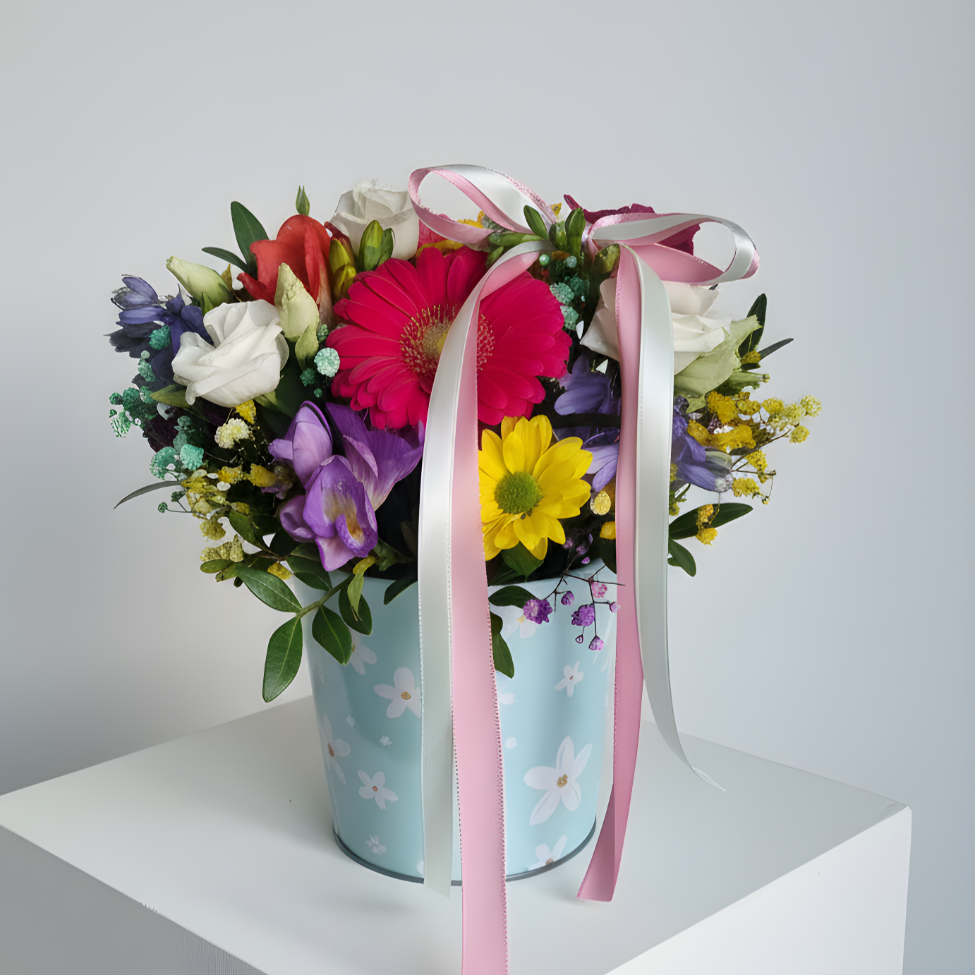 Arranjo floral colorido em vaso azul com fita rosa e branca