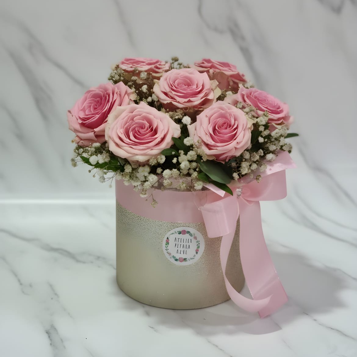 Arranjo floral em caixa com rosas cor de rosa e pequenas flores brancas