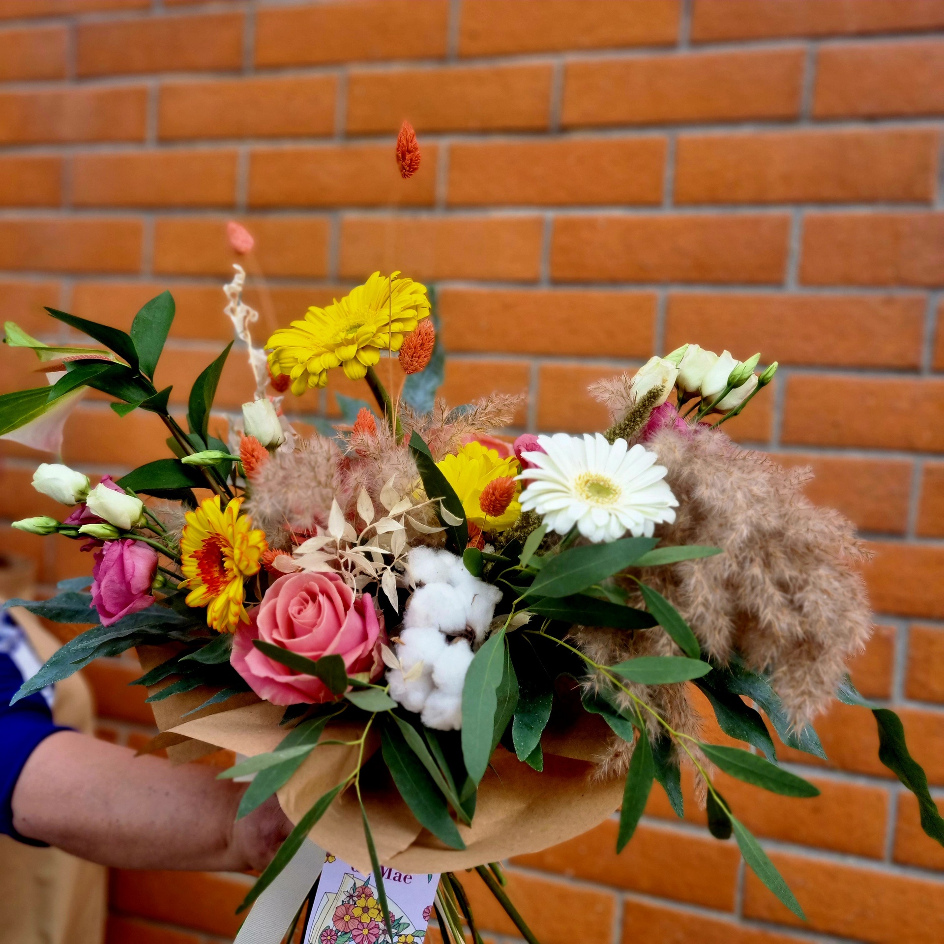 Ramo de flores coloridas com papel pardo e parede de tijolo ao fundo