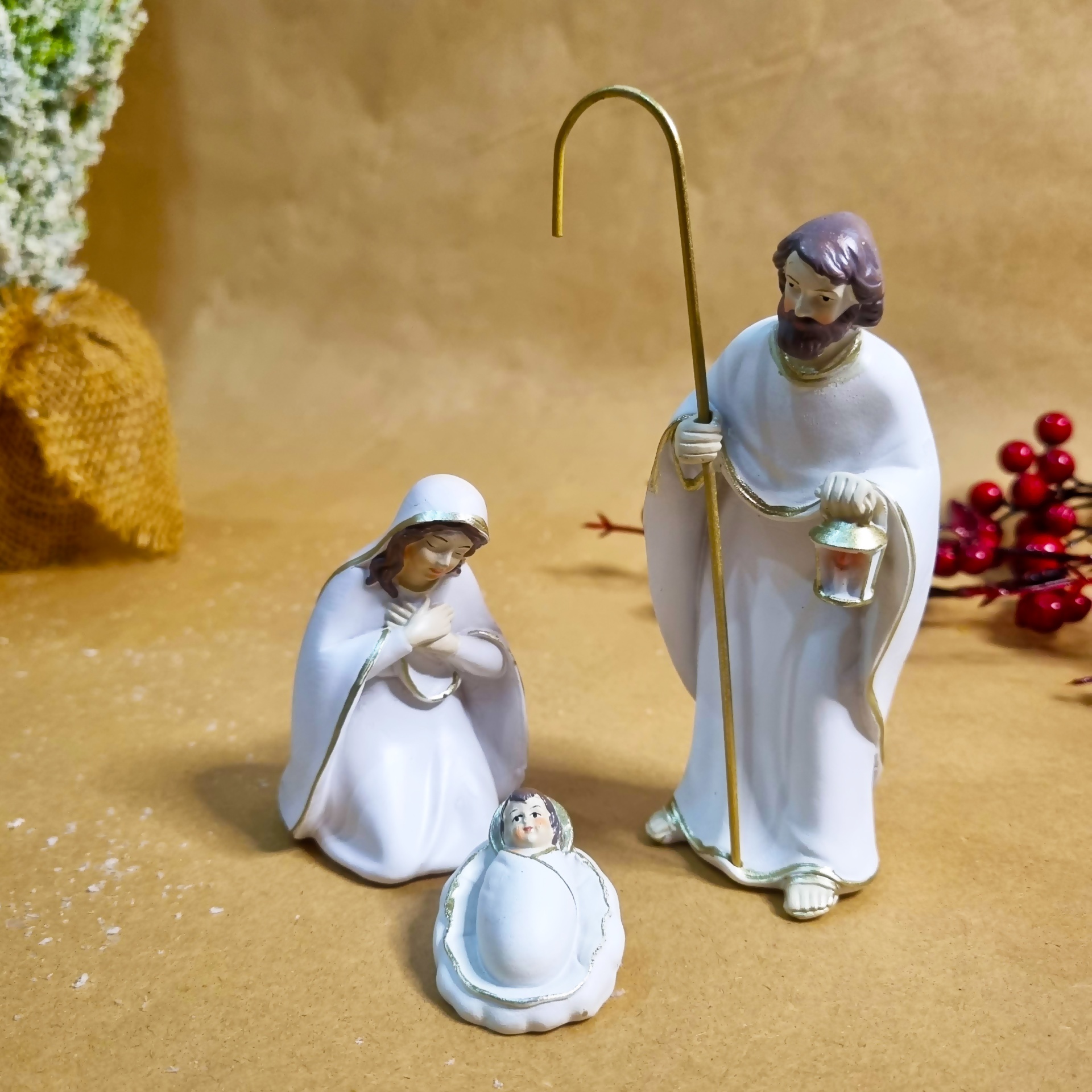 Conjunto de estatuetas religiosas de Maria, José e Menino Jesus em fundo castanho claro