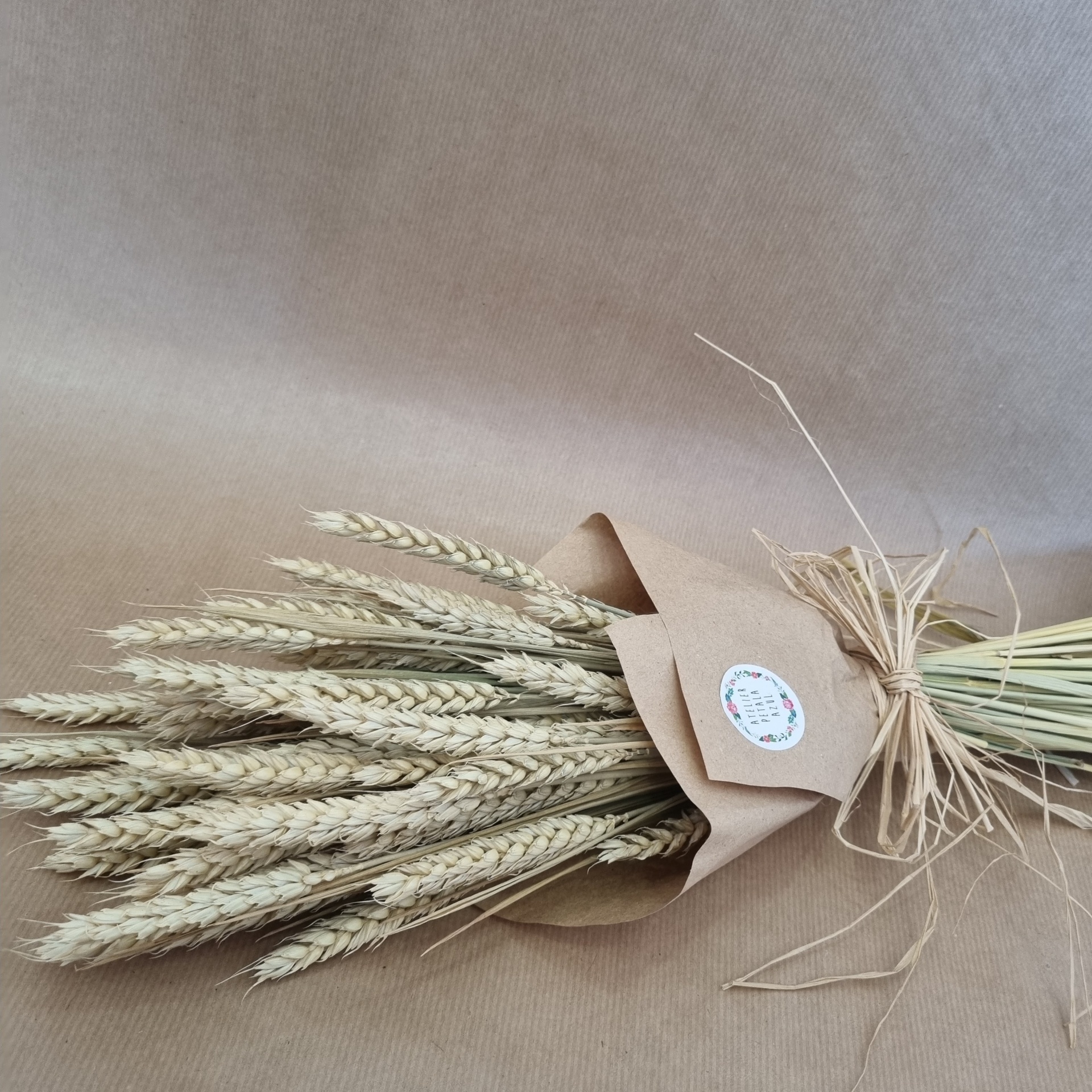 Ramo de espigas secas envolto em papel castanho com etiqueta e cordão rústico