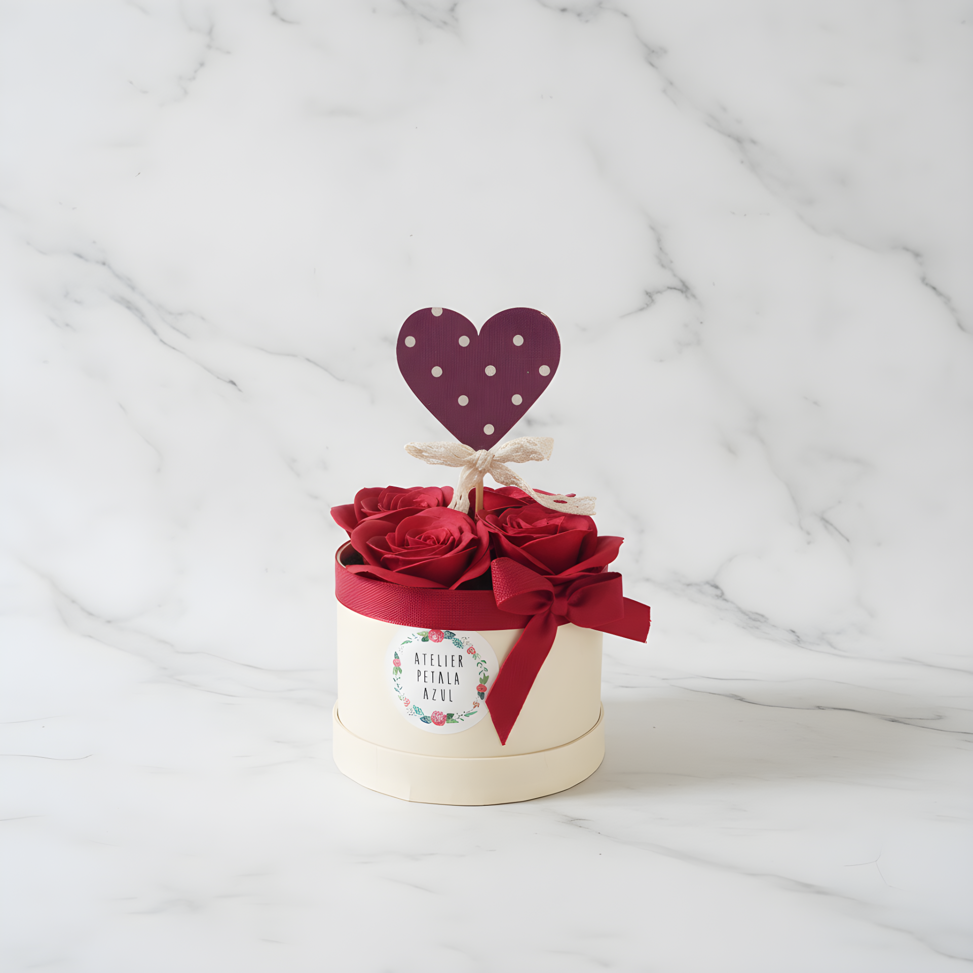 Arranjo de rosas vermelhas em caixa creme com coração decorativo.